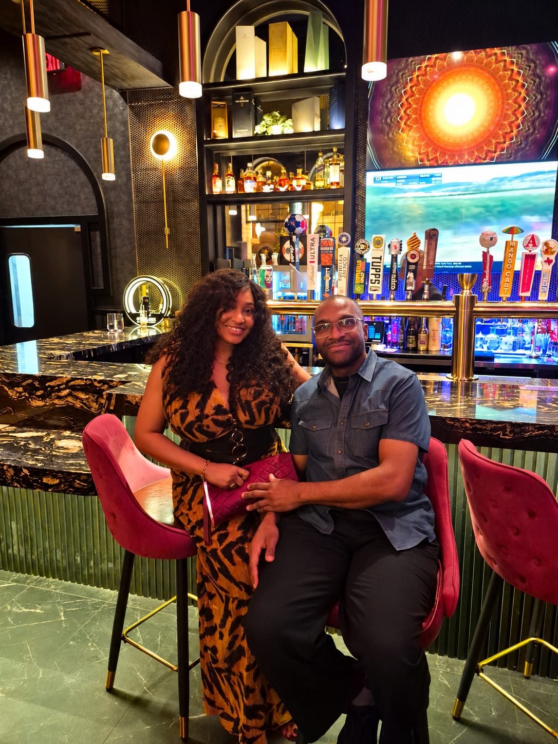 Lilian and Conrad seated together at an elegant bar